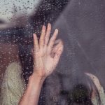 Emotional woman with her hand on a window.